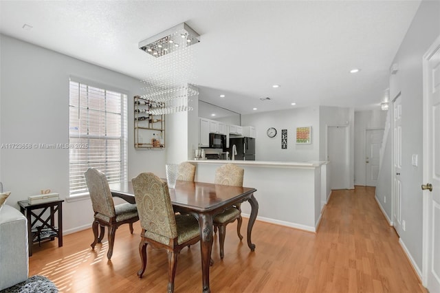 dining space featuring a chandelier, a healthy amount of sunlight, and light hardwood / wood-style flooring