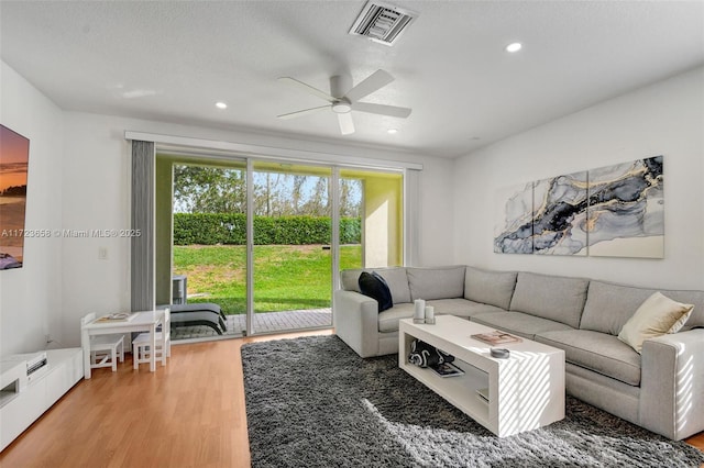 living room with ceiling fan, a textured ceiling, and light hardwood / wood-style flooring