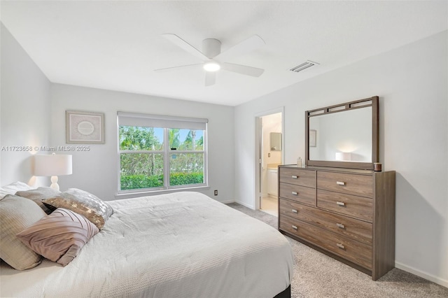 bedroom featuring ceiling fan, light colored carpet, and ensuite bath