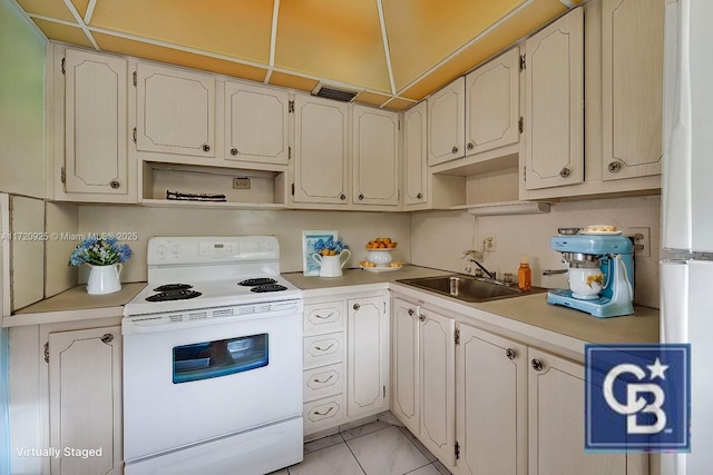 kitchen with refrigerator, sink, light tile patterned floors, electric range, and white cabinetry