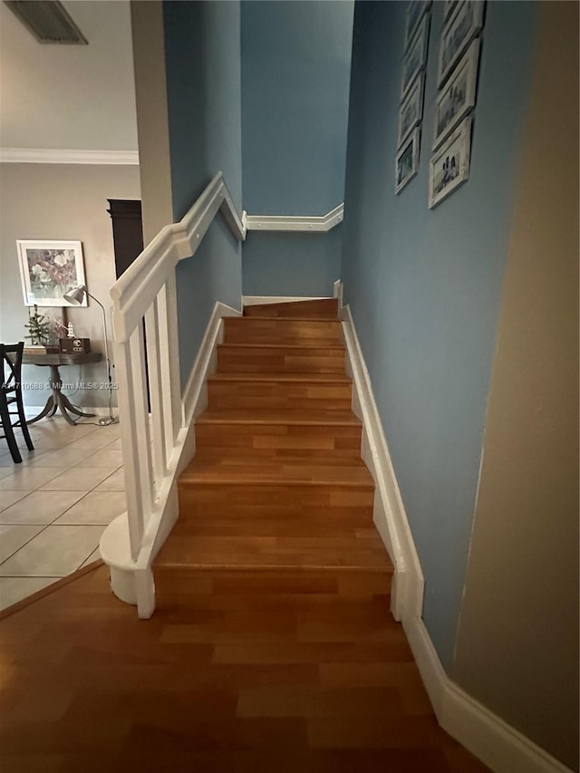 stairs with tile patterned flooring and crown molding