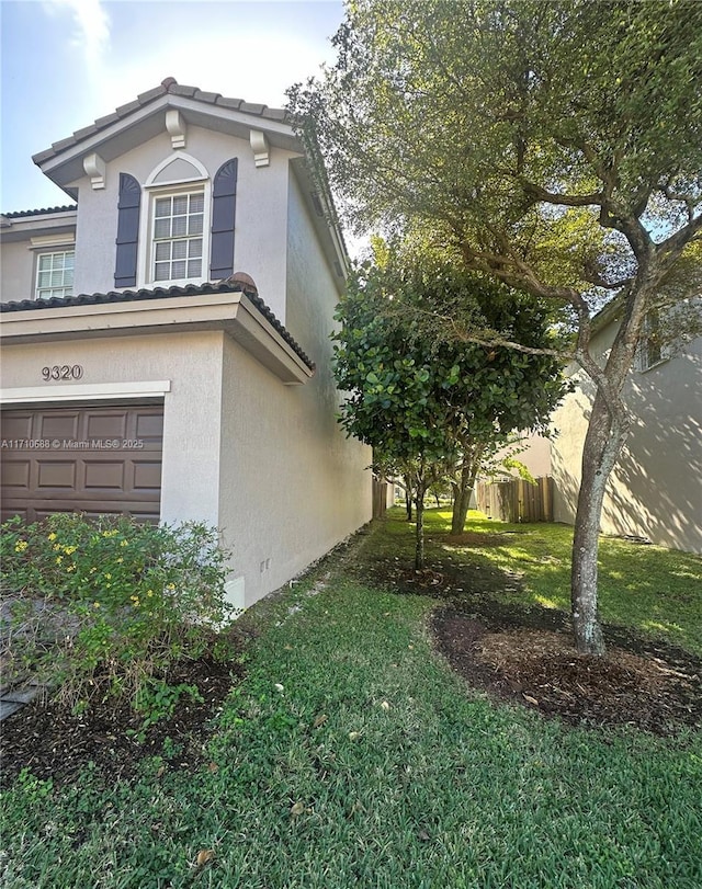 view of property exterior featuring a garage and a lawn