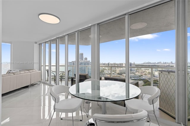 tiled dining space featuring a wall of windows and a water view