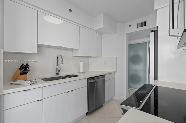 kitchen featuring stainless steel dishwasher, a sink, light tile patterned floors, white cabinets, and visible vents