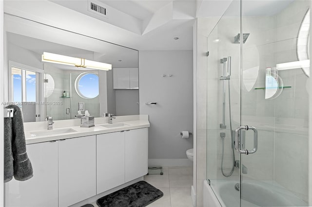 full bathroom with tile patterned floors, bath / shower combo with glass door, vanity, and toilet