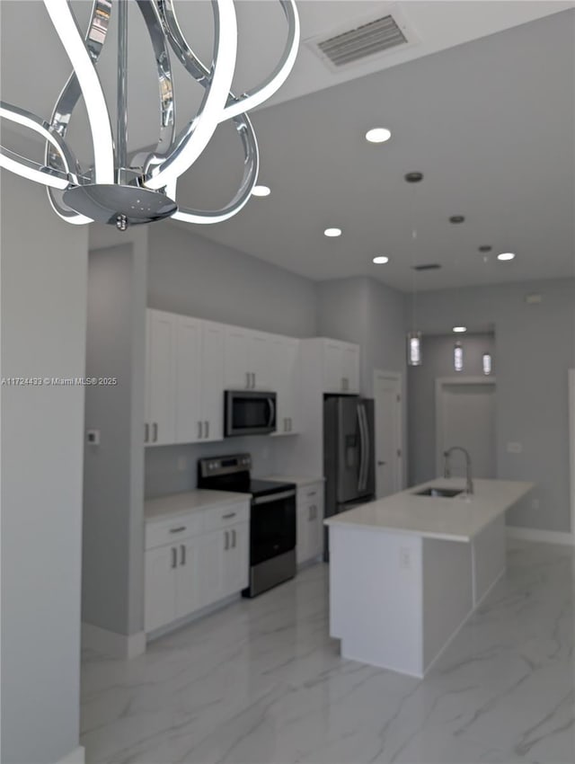 kitchen with an inviting chandelier, white cabinets, a center island with sink, sink, and stainless steel appliances