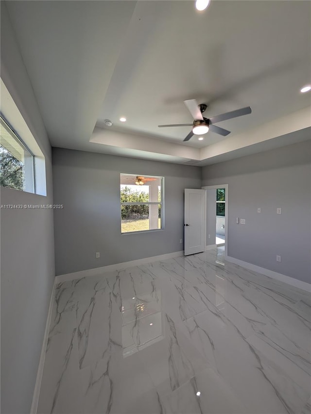 empty room featuring a raised ceiling and ceiling fan