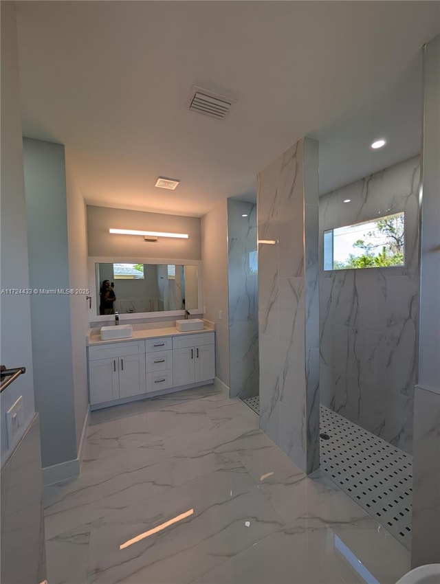 bathroom with a tile shower, plenty of natural light, and vanity