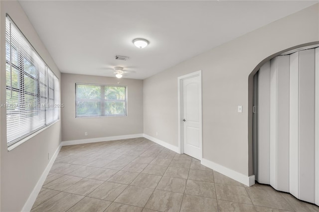 empty room with ceiling fan and light tile patterned flooring