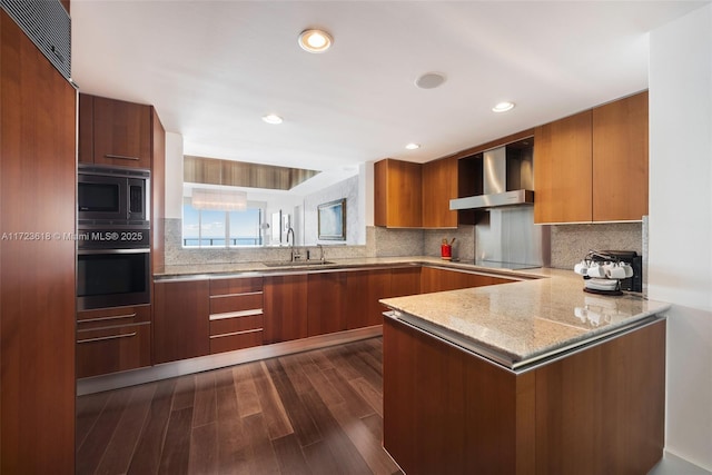 kitchen with kitchen peninsula, sink, wall chimney range hood, black appliances, and dark hardwood / wood-style floors