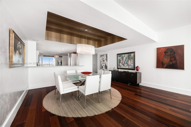 dining space with a raised ceiling and dark wood-type flooring