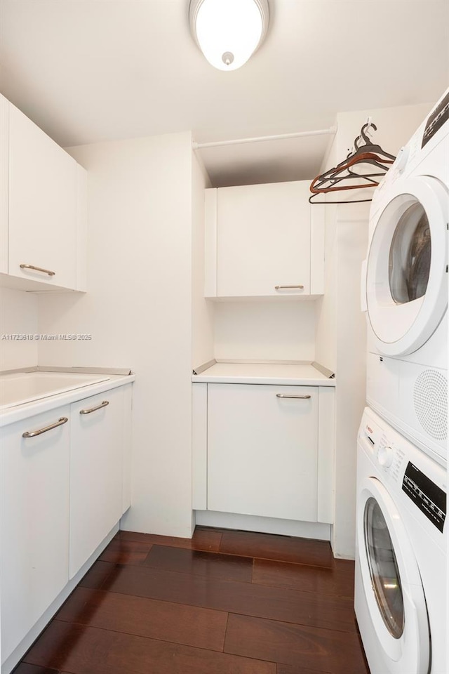 clothes washing area with sink, cabinets, stacked washing maching and dryer, and dark wood-type flooring