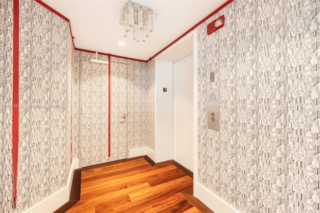 bathroom featuring hardwood / wood-style flooring, ornamental molding, and elevator