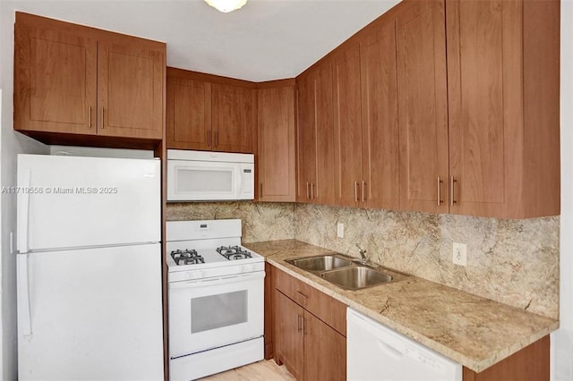 kitchen with light stone countertops, sink, tasteful backsplash, and white appliances