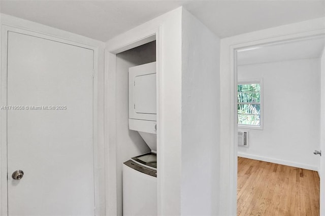 clothes washing area with light hardwood / wood-style floors, stacked washer / drying machine, and an AC wall unit