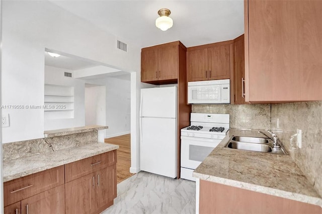 kitchen with light stone countertops, decorative backsplash, sink, and white appliances