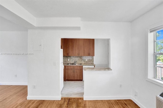 kitchen featuring decorative backsplash, light hardwood / wood-style floors, sink, and plenty of natural light