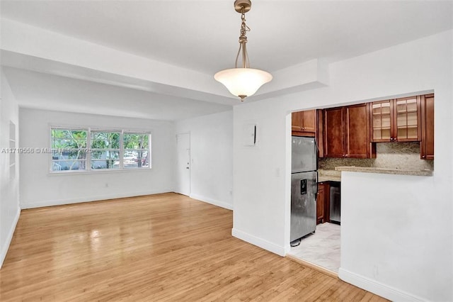 kitchen with stainless steel refrigerator with ice dispenser, light hardwood / wood-style floors, backsplash, and decorative light fixtures