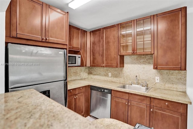 kitchen featuring decorative backsplash, light stone countertops, sink, and stainless steel appliances