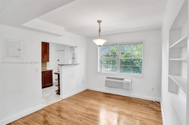 empty room with light hardwood / wood-style floors, electric panel, and a wall mounted AC