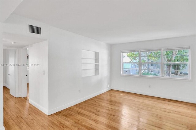 unfurnished room with built in features and light hardwood / wood-style flooring