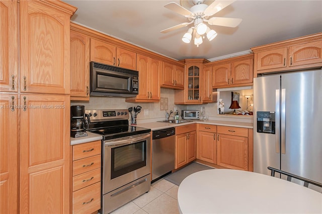 kitchen with ceiling fan, sink, tasteful backsplash, light tile patterned floors, and appliances with stainless steel finishes