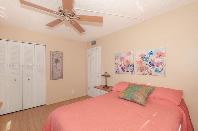 bedroom with light wood-type flooring, a textured ceiling, a closet, and ceiling fan