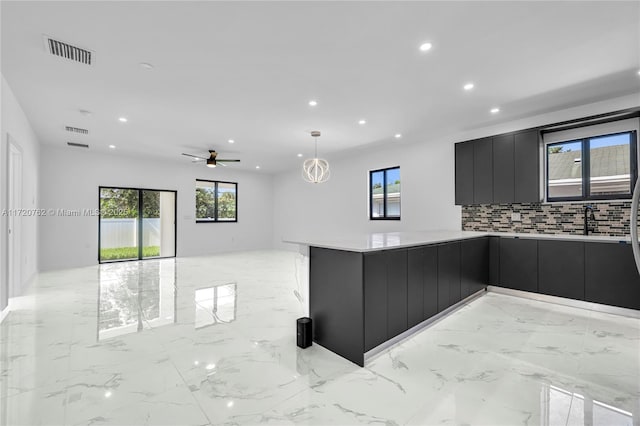 kitchen featuring kitchen peninsula, backsplash, ceiling fan, sink, and hanging light fixtures