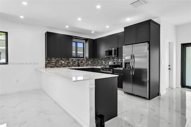 kitchen featuring kitchen peninsula, decorative backsplash, and appliances with stainless steel finishes