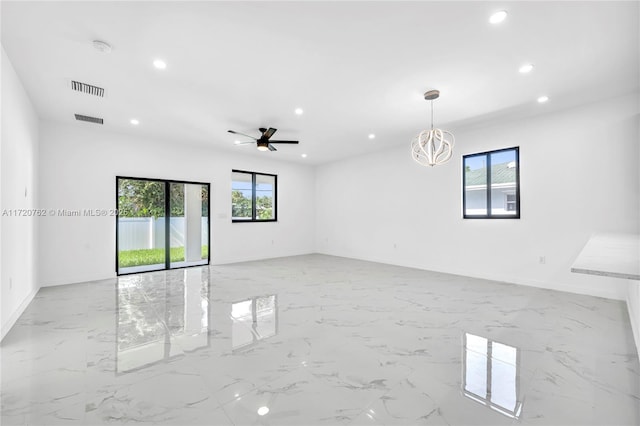 spare room featuring ceiling fan with notable chandelier