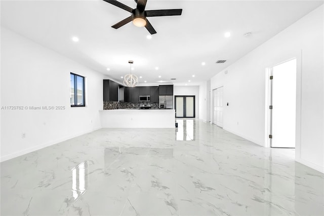 unfurnished living room with ceiling fan with notable chandelier