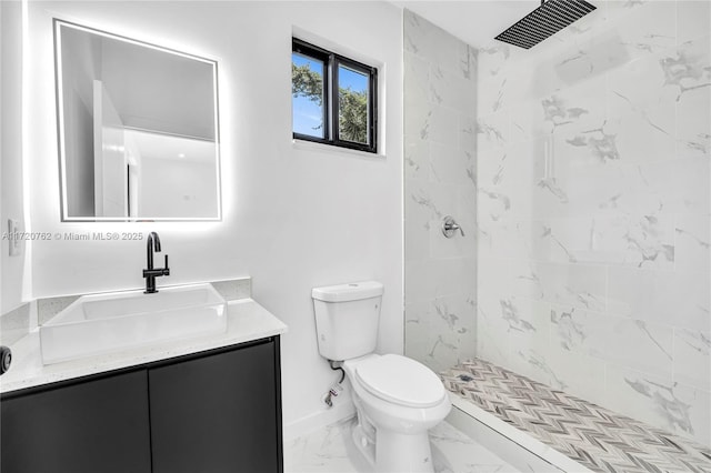 bathroom with a tile shower, vanity, and toilet