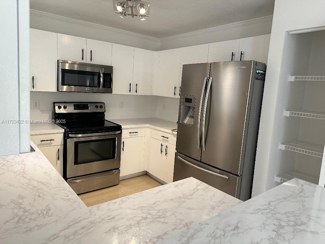 kitchen featuring white cabinetry, light tile patterned floors, stainless steel appliances, and ornamental molding