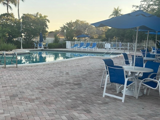 pool at dusk with a patio area