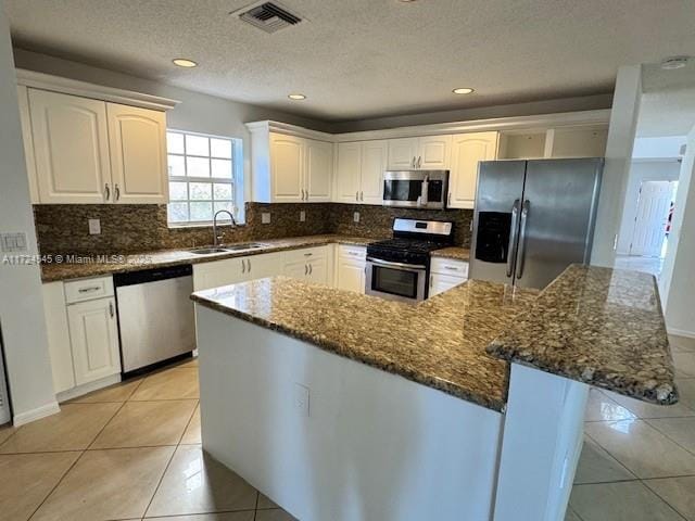 kitchen with stainless steel appliances, a center island, sink, and white cabinets