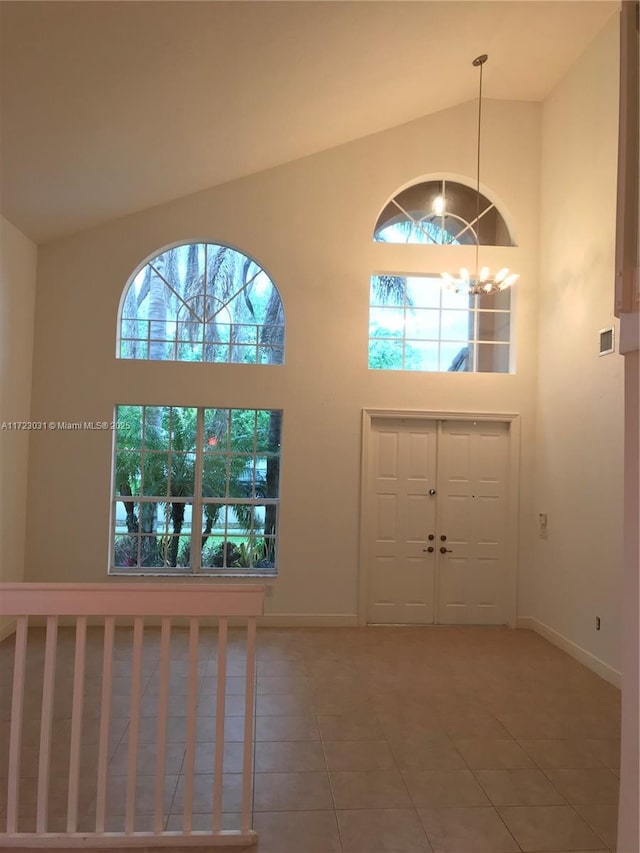 entryway with tile patterned floors, an inviting chandelier, and high vaulted ceiling