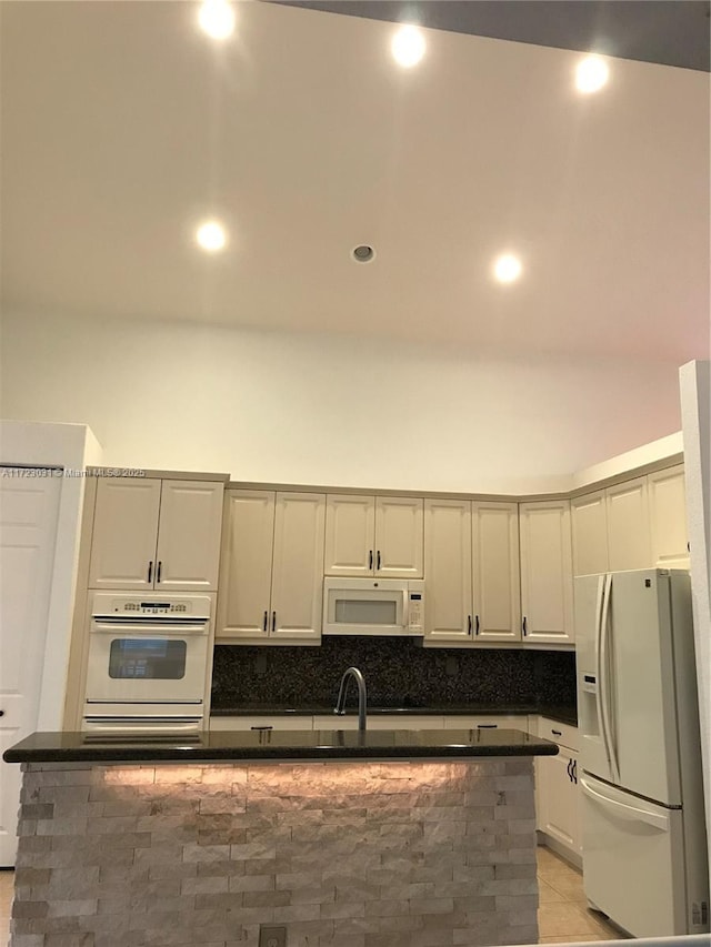 kitchen with decorative backsplash, light tile patterned flooring, and white appliances