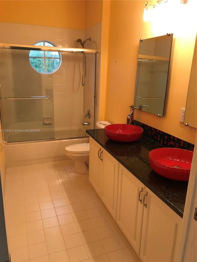 full bathroom featuring combined bath / shower with glass door, vanity, tile patterned floors, and toilet