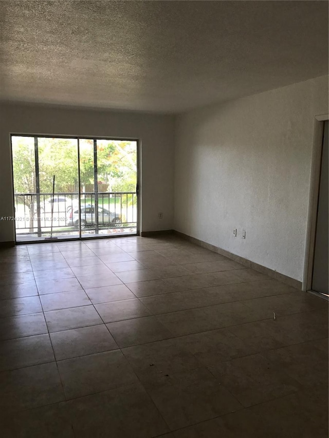 tiled empty room featuring a wealth of natural light and a textured ceiling