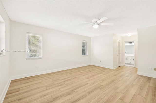 spare room with ceiling fan, light wood-type flooring, and a textured ceiling