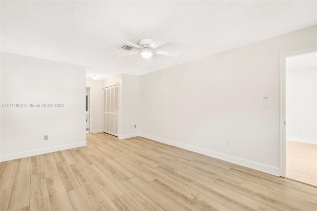 empty room featuring ceiling fan, light hardwood / wood-style floors, and a textured ceiling