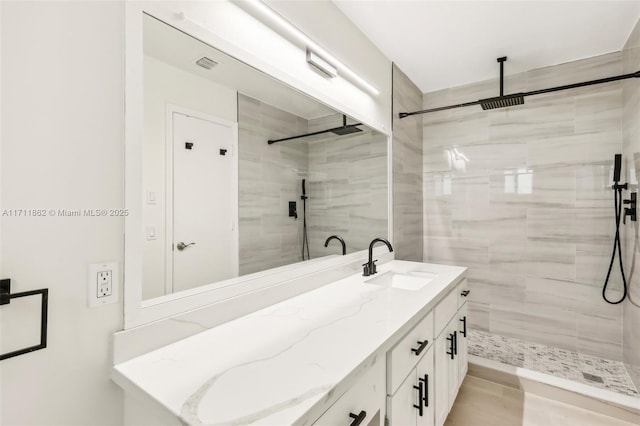 bathroom with a tile shower and vanity