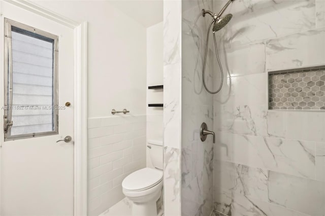 bathroom with toilet, tile walls, and tiled shower