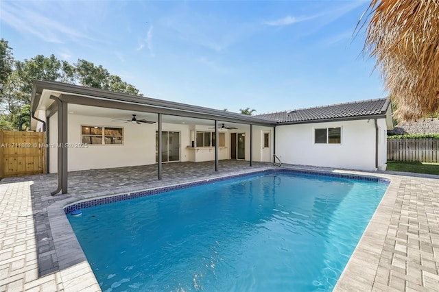 back of property featuring ceiling fan, a patio area, and a fenced in pool