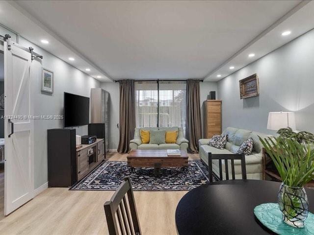 living room with a barn door and light hardwood / wood-style flooring