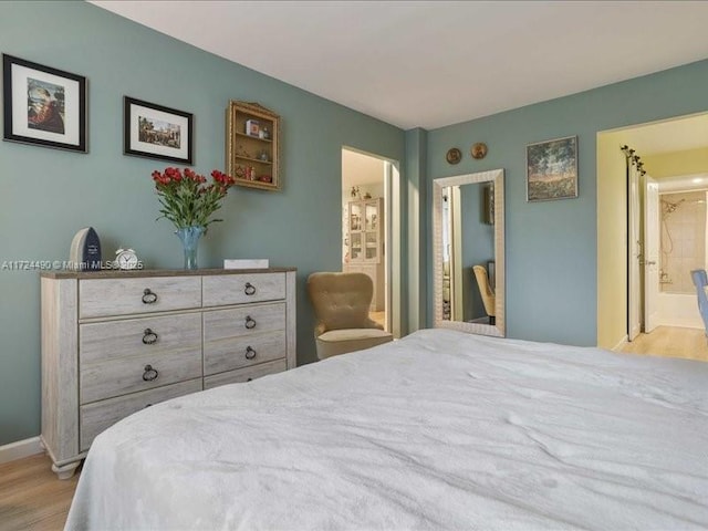 bedroom featuring ensuite bathroom and light hardwood / wood-style floors