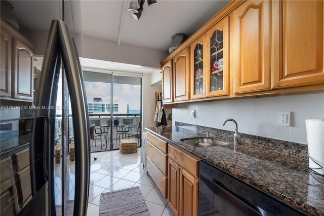 kitchen with light tile patterned floors, floor to ceiling windows, dark stone countertops, and sink