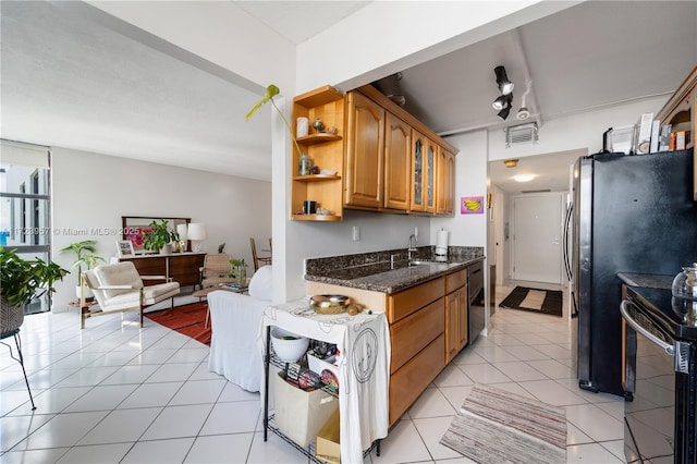 kitchen with sink, electric range oven, dark stone countertops, fridge, and light tile patterned flooring