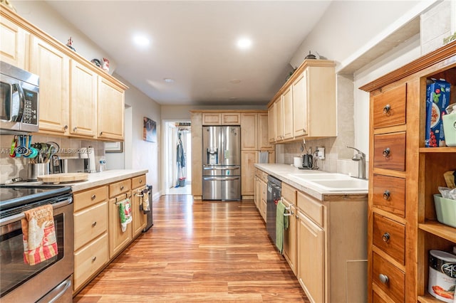 kitchen with light brown cabinets, backsplash, sink, light wood-type flooring, and stainless steel appliances