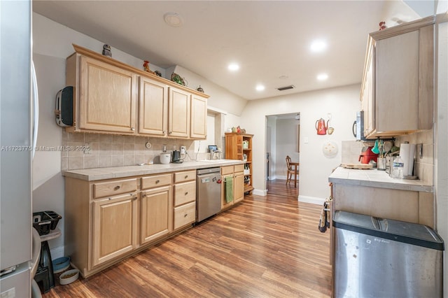 kitchen with light brown cabinets, stainless steel appliances, backsplash, tile countertops, and hardwood / wood-style floors